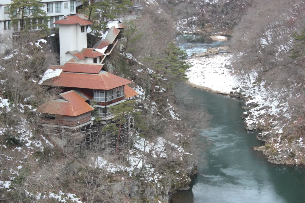 雪景色の中流れる川のほとりに位置する温泉街