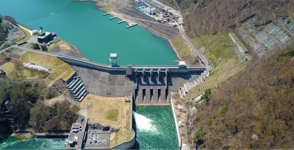 青い水面が美しいダム湖と巨大な大川ダムを上空から見た様子