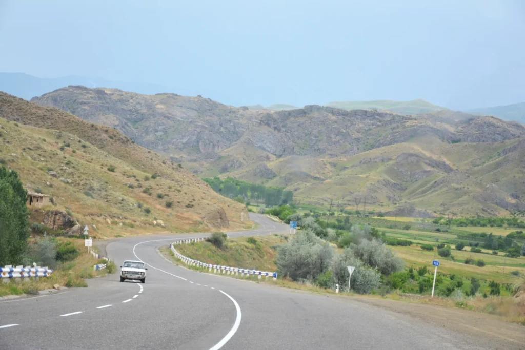 A Single Car Driving Along a Road Through the Mountains