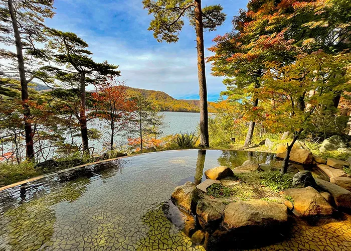 紅葉に囲まれた露天風呂と間から見える湖畔