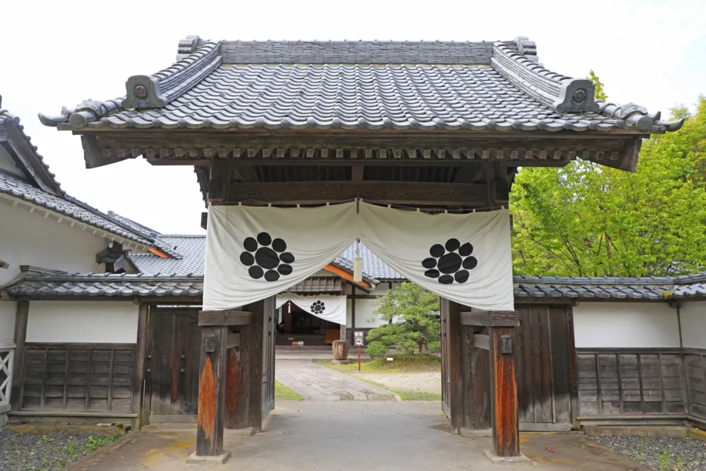 木造の家老屋敷。家の門には白い垂れ幕がかかっている。