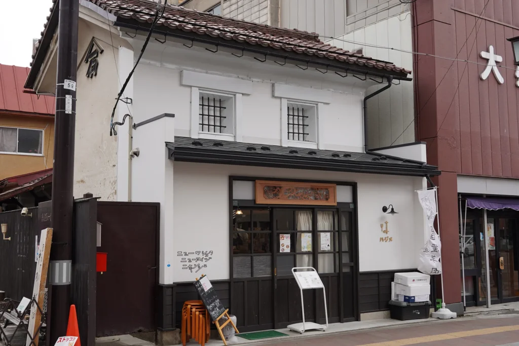 二階建てのコンパクトな飲食店。白壁と瓦屋根の建物。